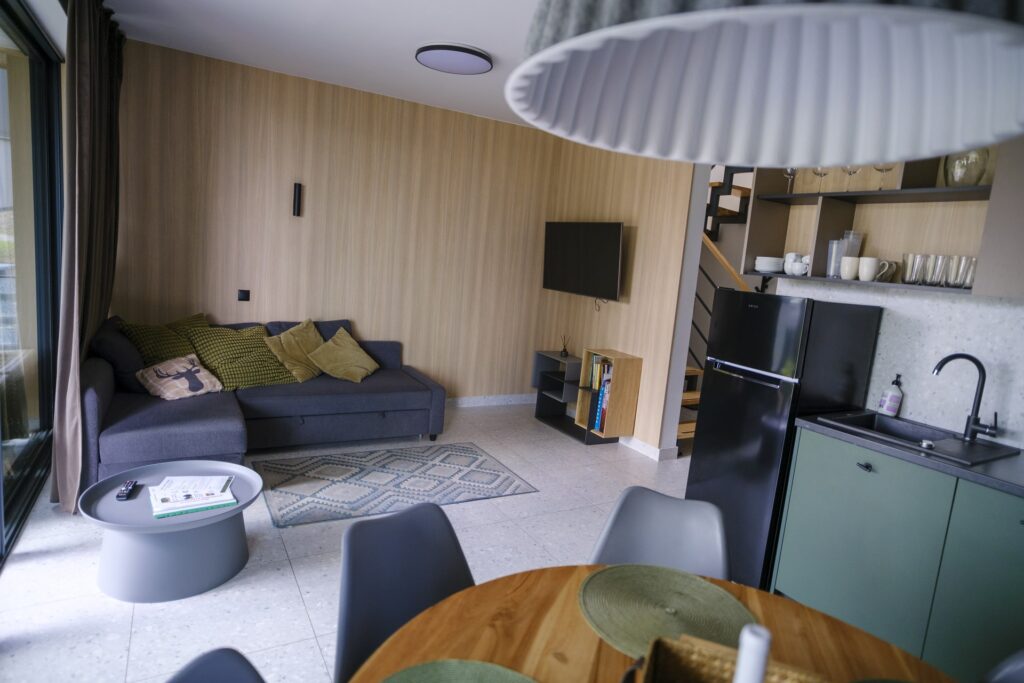 Część dzienna domu w Campo Resort - narożnik do spania, stół jadalny i aneks kuchenny