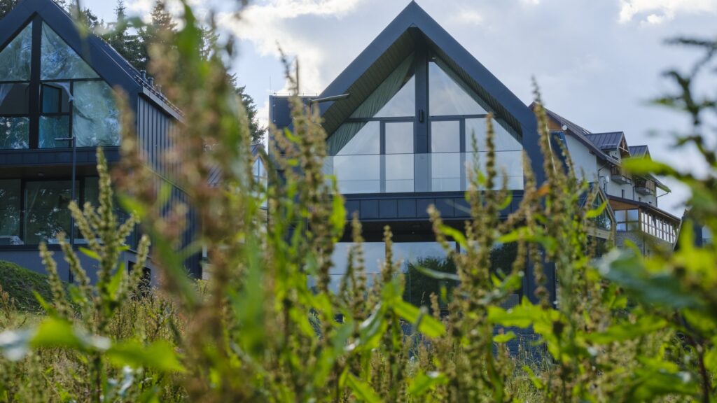 Dom Campo Resort w Zieleńcu widziany przez łąkę, jesienne światło nad Górami Orlickimi